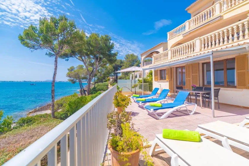 A seaside terrace with lounge seating overlooks the blue water.