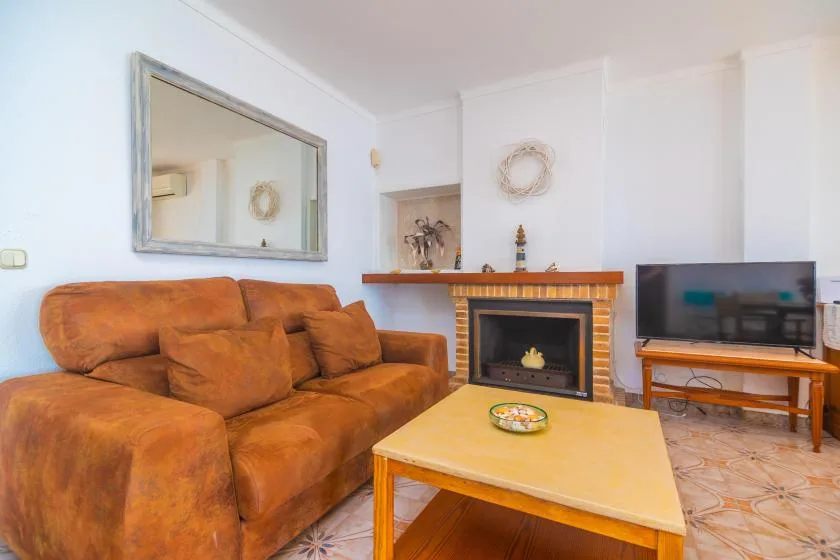 A living room with brown seating, a fireplace, and a television.