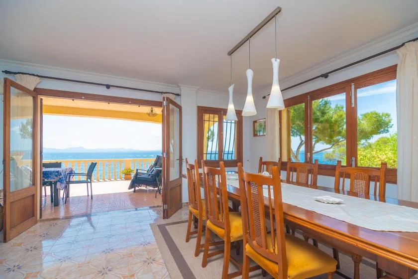 A dining area opens onto a balcony with a view of the sea.