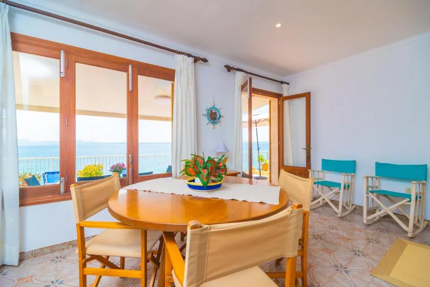A dining area with a round wooden table beside windows overlooking the water.