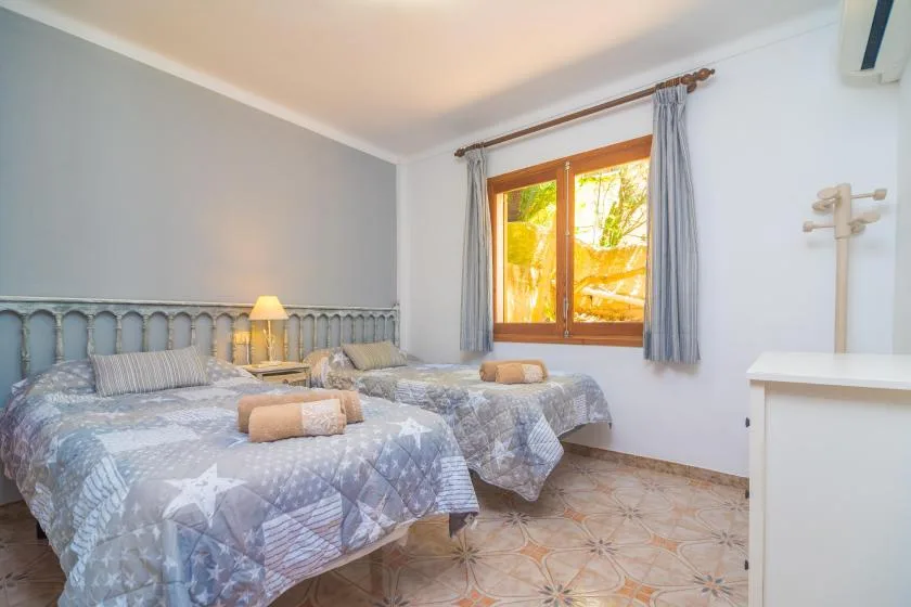 A bedroom with two beds and a window framed by gray curtains.