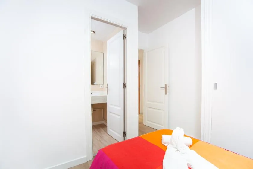 Un dormitorio con una cama colorida y una puerta abierta hacia un baño.
