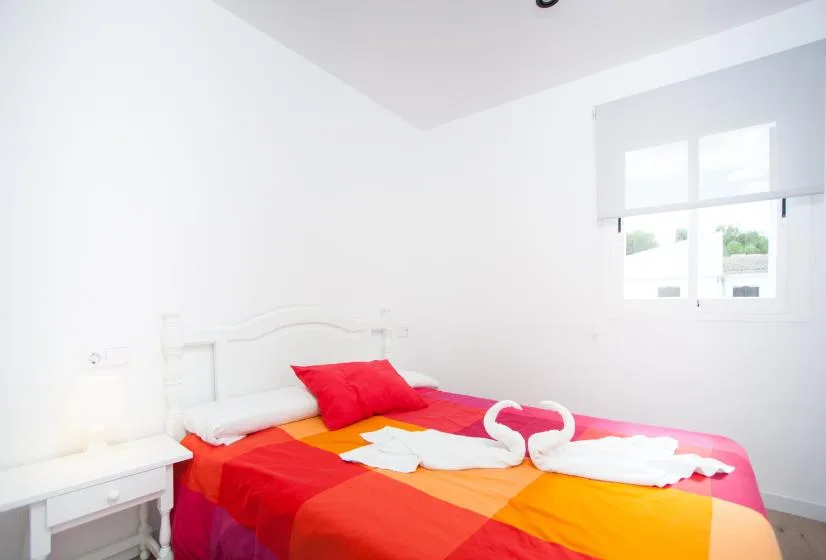 Un dormitorio con una cama cubierta con una colcha de colores rojo y naranja.