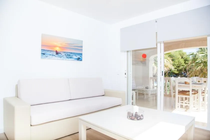 Una sala luminosa con asientos blancos y una vista abierta a un comedor exterior.
