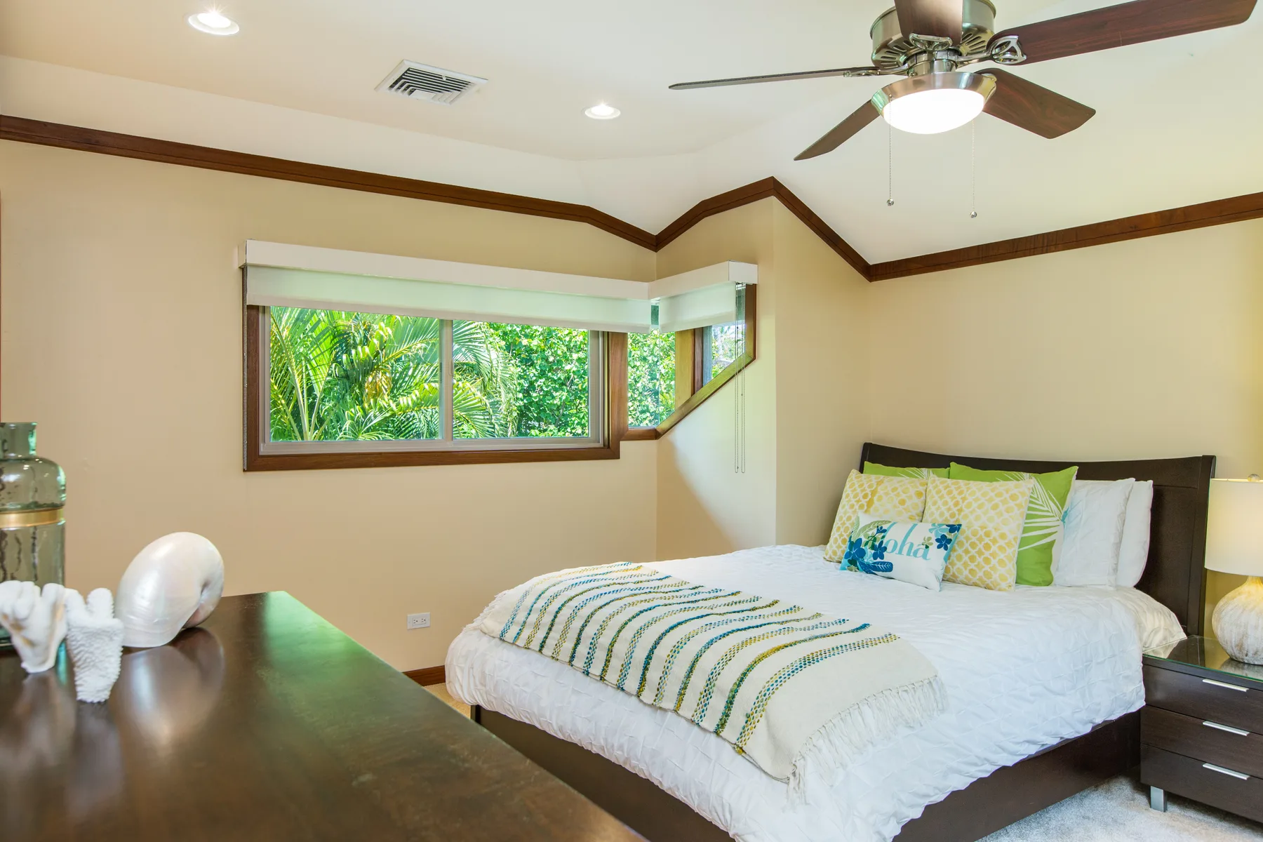Dormitorio con una cama bien hecha y una ventana amplia con vista a la vegetación.