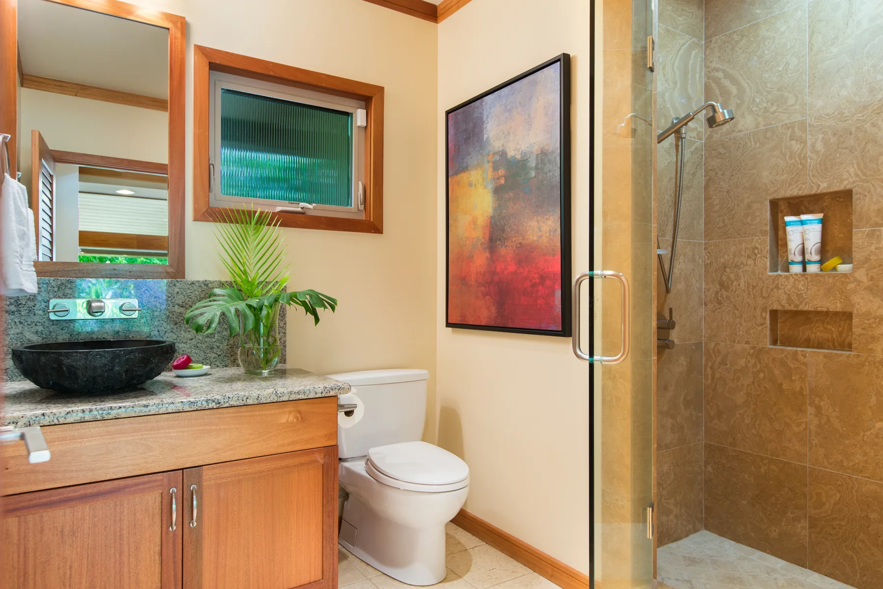 Un baño con lavabo, inodoro y ducha con mampara de vidrio.
