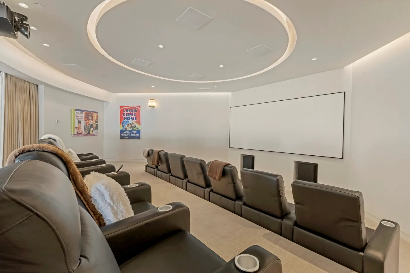 A home theater with rows of reclining seats facing a large screen.