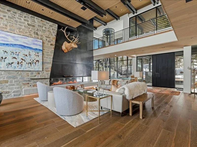 A spacious living room with a dining area, tall windows, and a fireplace.
