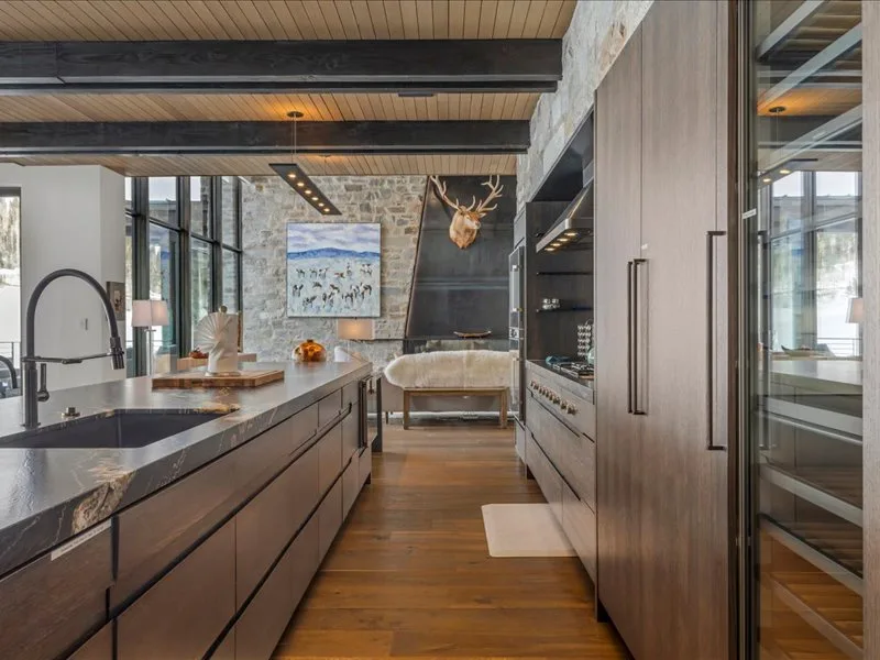 A modern kitchen with a long island and large windows.