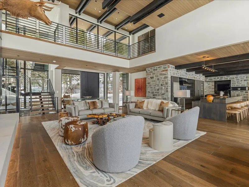 A spacious living room with seating arranged around a low table beside an open kitchen.