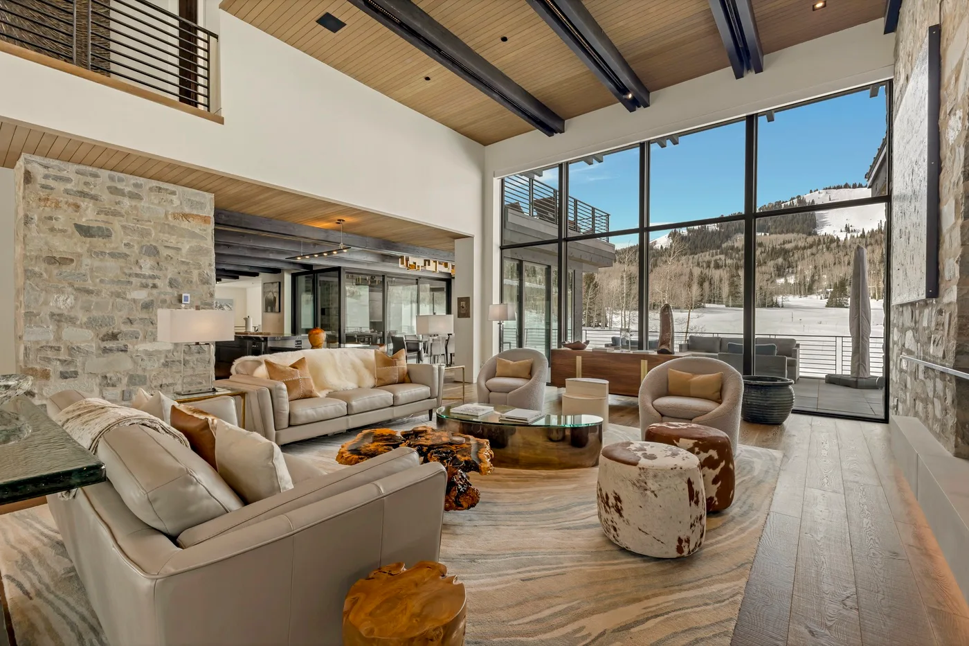 A spacious living room with seating, a coffee table, and large windows overlooking the mountains.