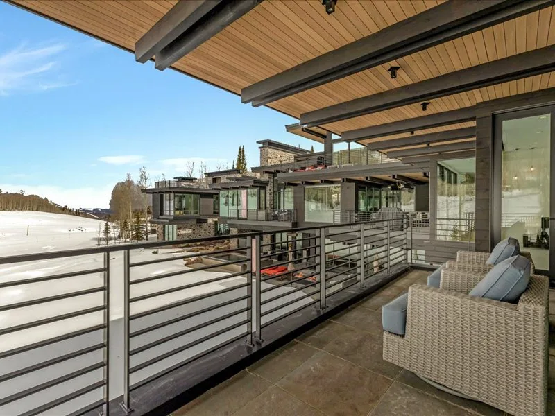 A covered outdoor seating area overlooks a snowy landscape and nearby modern buildings.