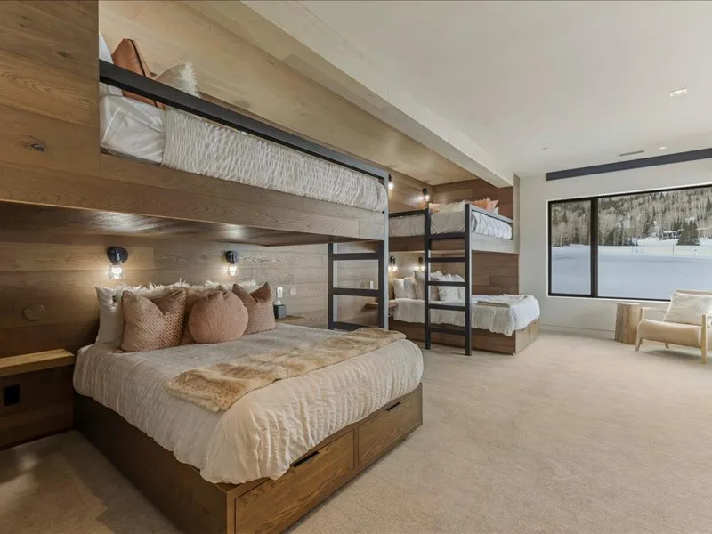 A bedroom with bunk beds and a large window overlooking a snowy landscape.