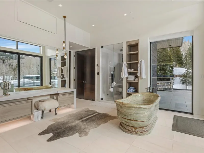 A bright modern bathroom features a freestanding bathtub beside a glass shower.