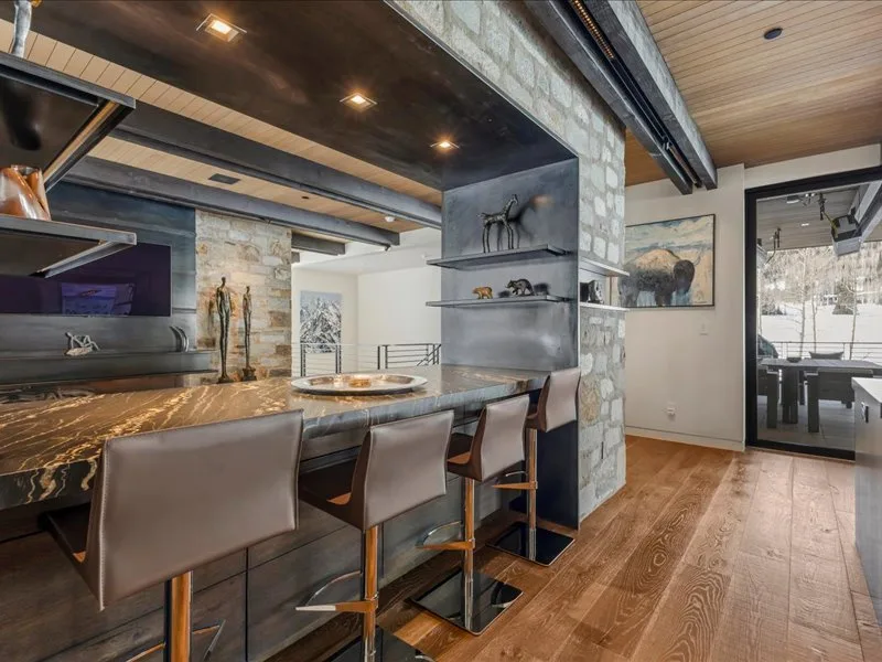 A modern dining area with a long counter and seating beside a glass door.