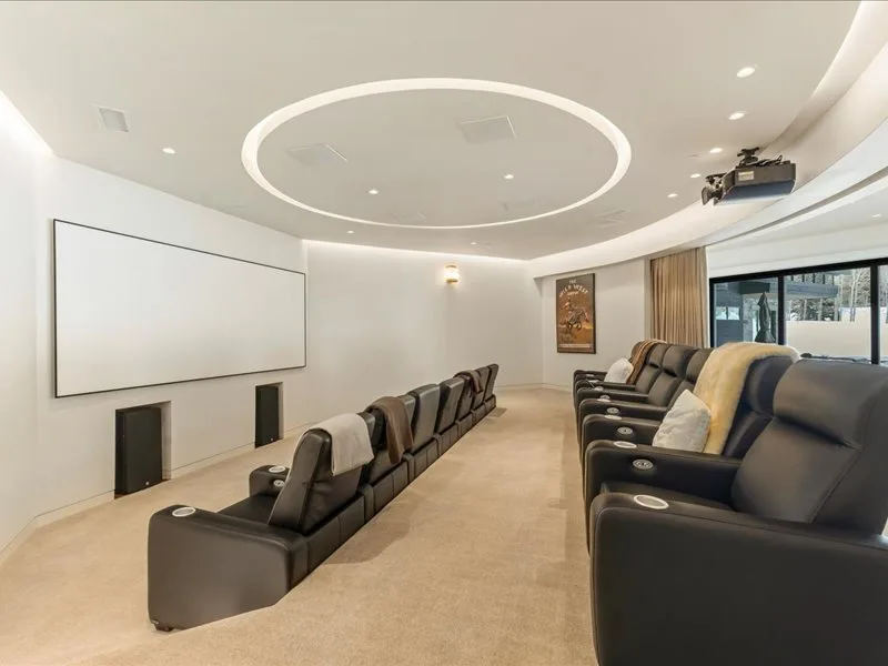 A home theater with rows of seating facing a large projection screen.