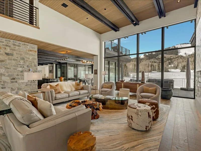 A spacious living room with seating arranged around a low table and large windows.