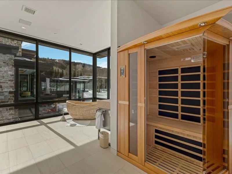 A bright spa area features a wooden sauna beside large windows.