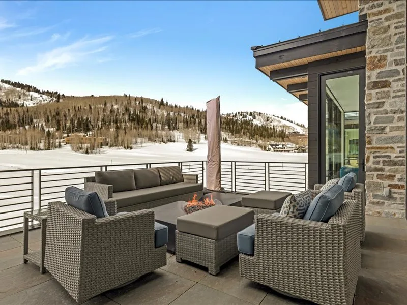 An outdoor patio seating area overlooks a snowy, tree-covered hillside.