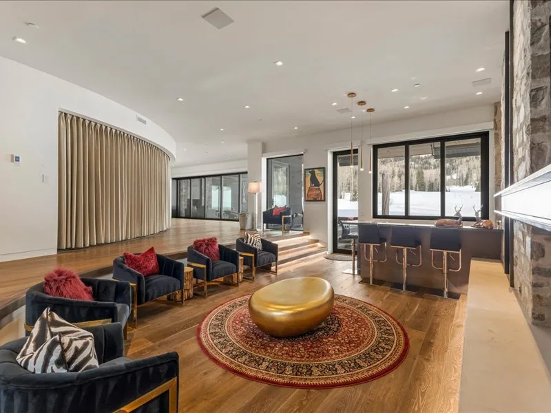 A modern lounge with seating arranged around a round table and patterned rug.