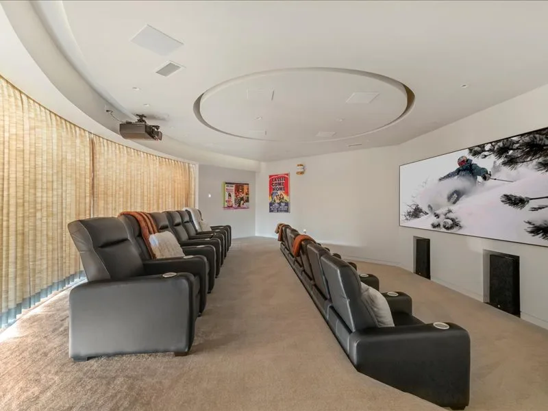 A screening room with rows of reclining seats facing a large wall display.