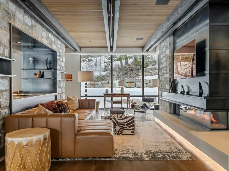 A modern living room with leather seating, a fireplace, and large windows.