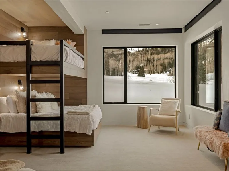 A bedroom with bunk beds and a seating area beside large windows.