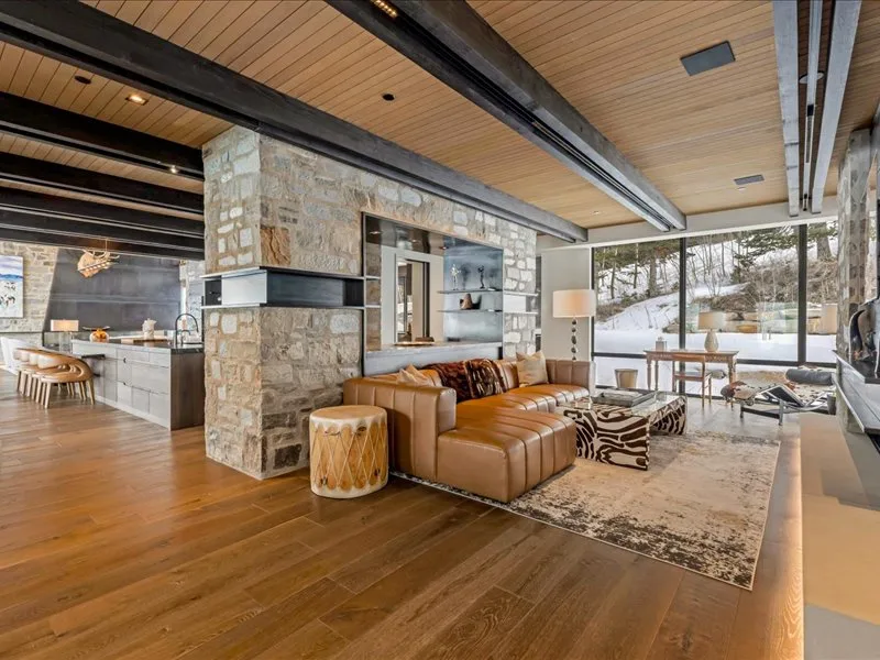 A spacious living room with a seating area beside large windows overlooking a snowy landscape.