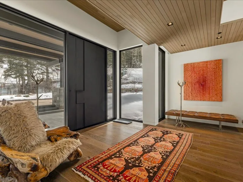 A modern living room with large glass doors, a patterned rug, and wall art.