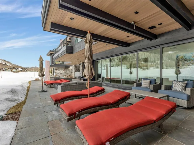 A modern outdoor patio with red lounge seating beside glass walls.