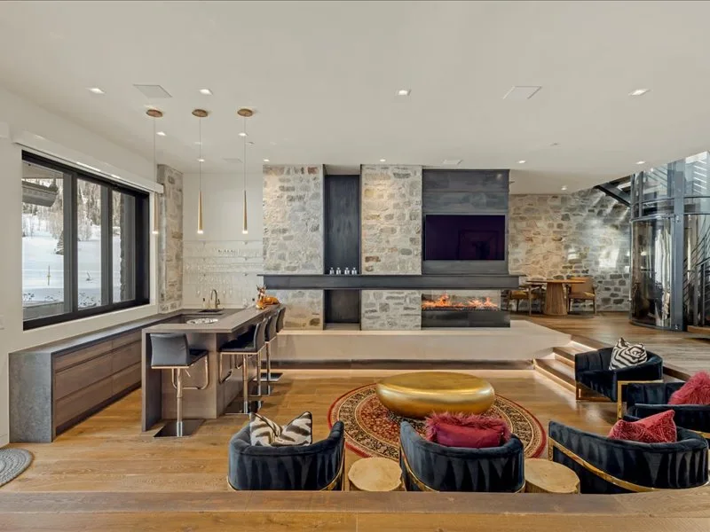 A spacious living room features a stone fireplace and seating around a low table.