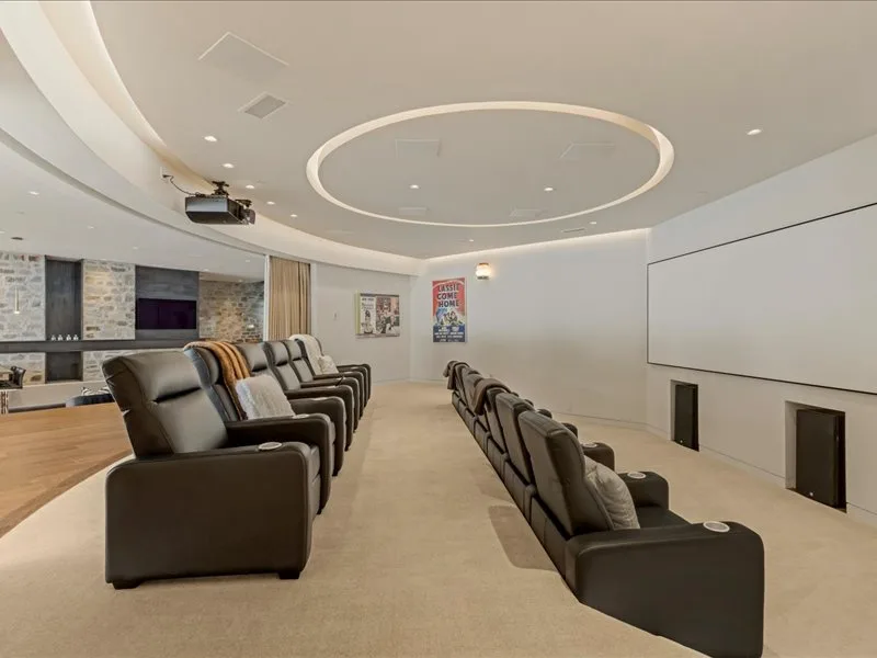 A theater-style seating area faces a large blank screen in a softly lit room.