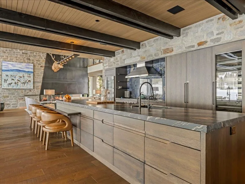 A spacious kitchen with a long island and bar seating beneath exposed ceiling beams.