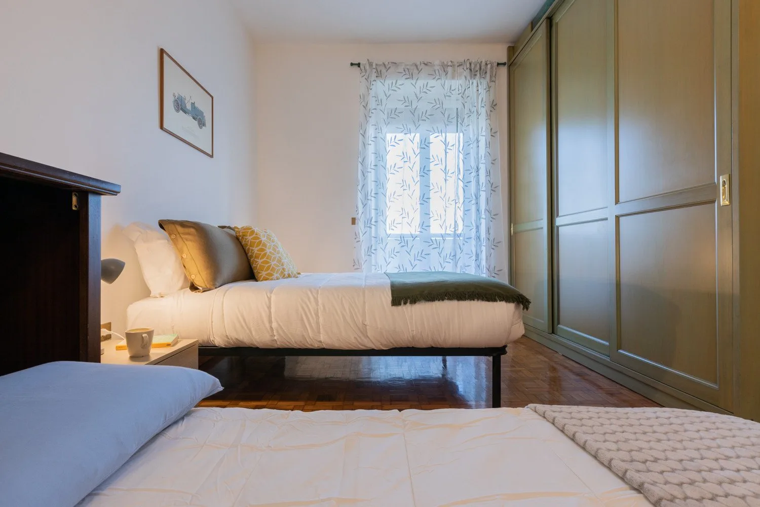 Un dormitorio con una cama elevada, una mesita de noche y armarios grandes.
