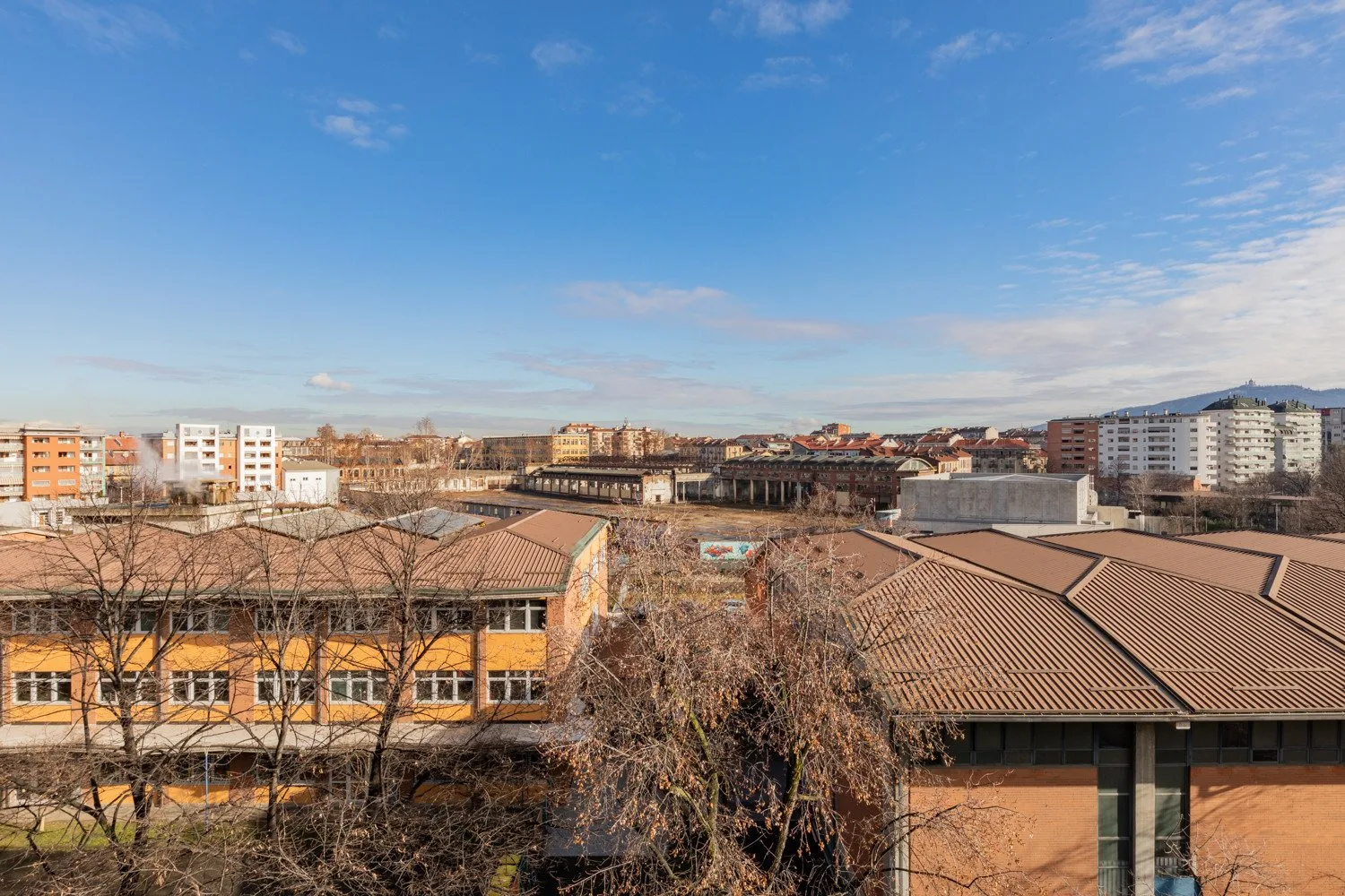 Un barrio urbano con edificios bajos y bloques de apartamentos bajo un cielo despejado.