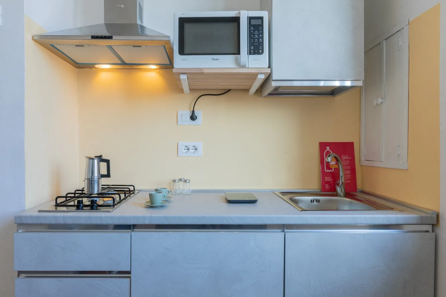 Una cocina compacta con estufa, microondas y fregadero junto a la encimera.