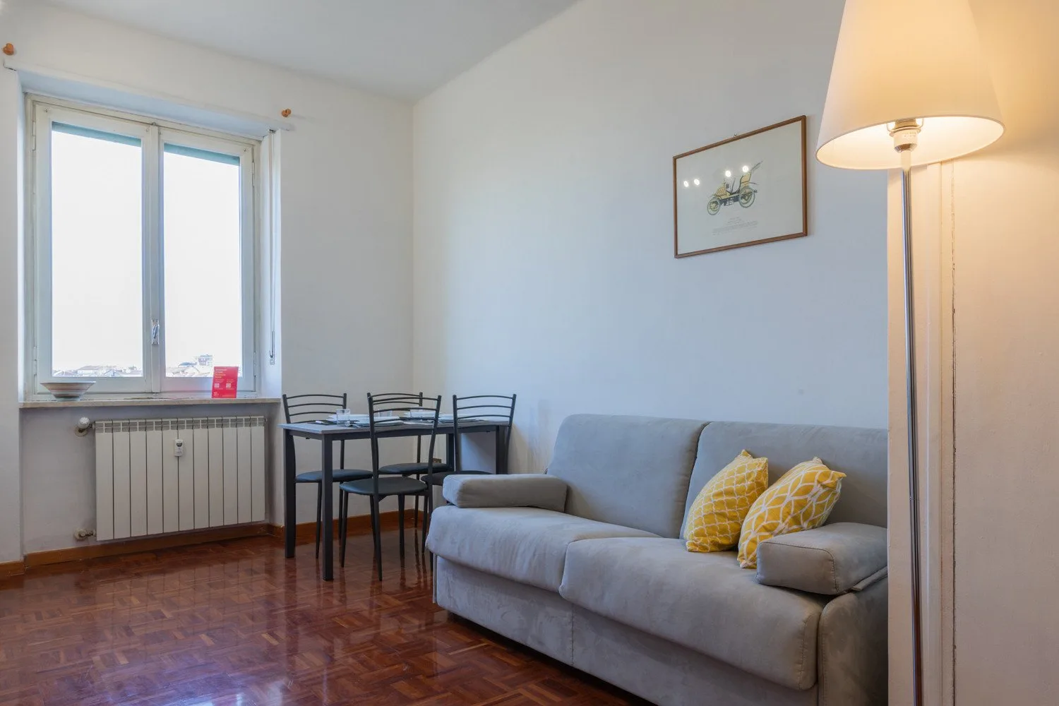 Una sala de estar con asientos junto a una pequeña mesa de comedor y una ventana amplia.