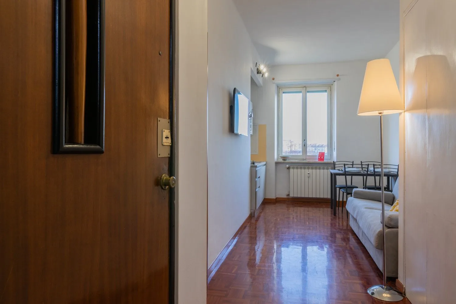Una sala estrecha con mesa de comedor, asientos y una ventana al fondo.