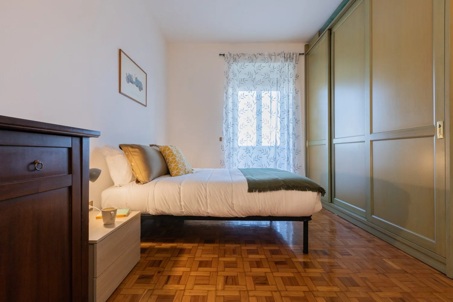 Un dormitorio con una cama junto a una ventana y armarios empotrados.