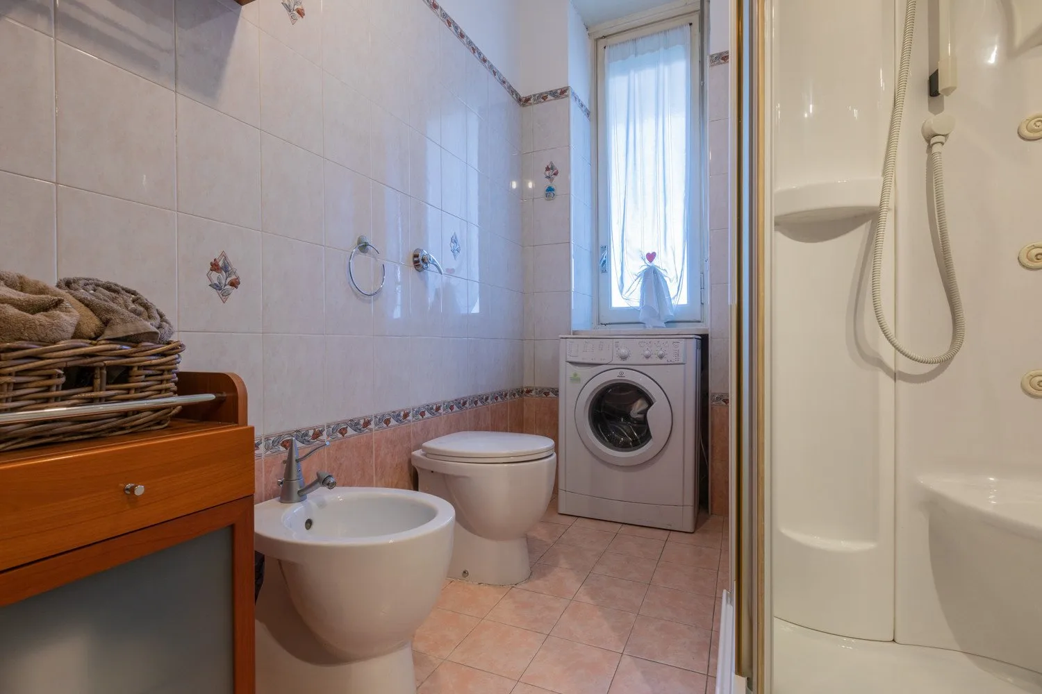 Un baño alicatado con lavabo, inodoro, lavadora y ducha.