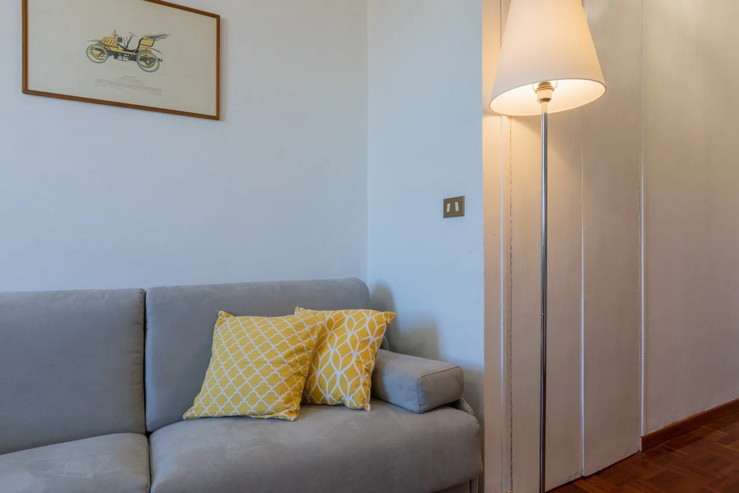 Una zona de estar con un sofá gris y cojines amarillos estampados.