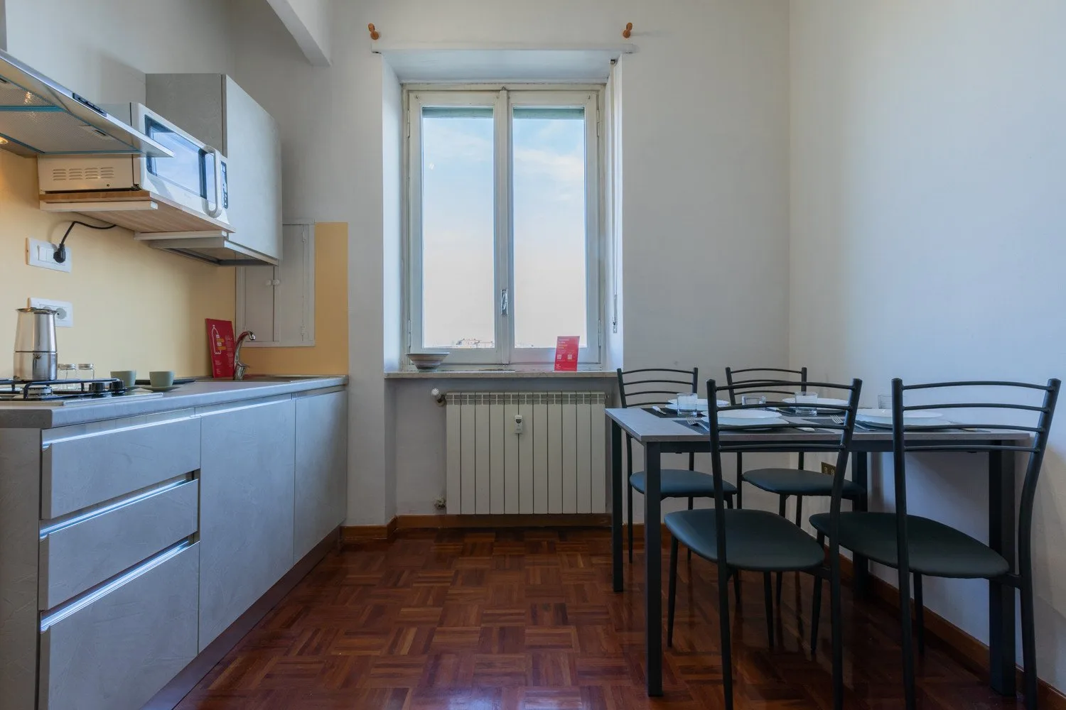 Una cocina compacta y zona de comedor con una mesa junto a una ventana grande.