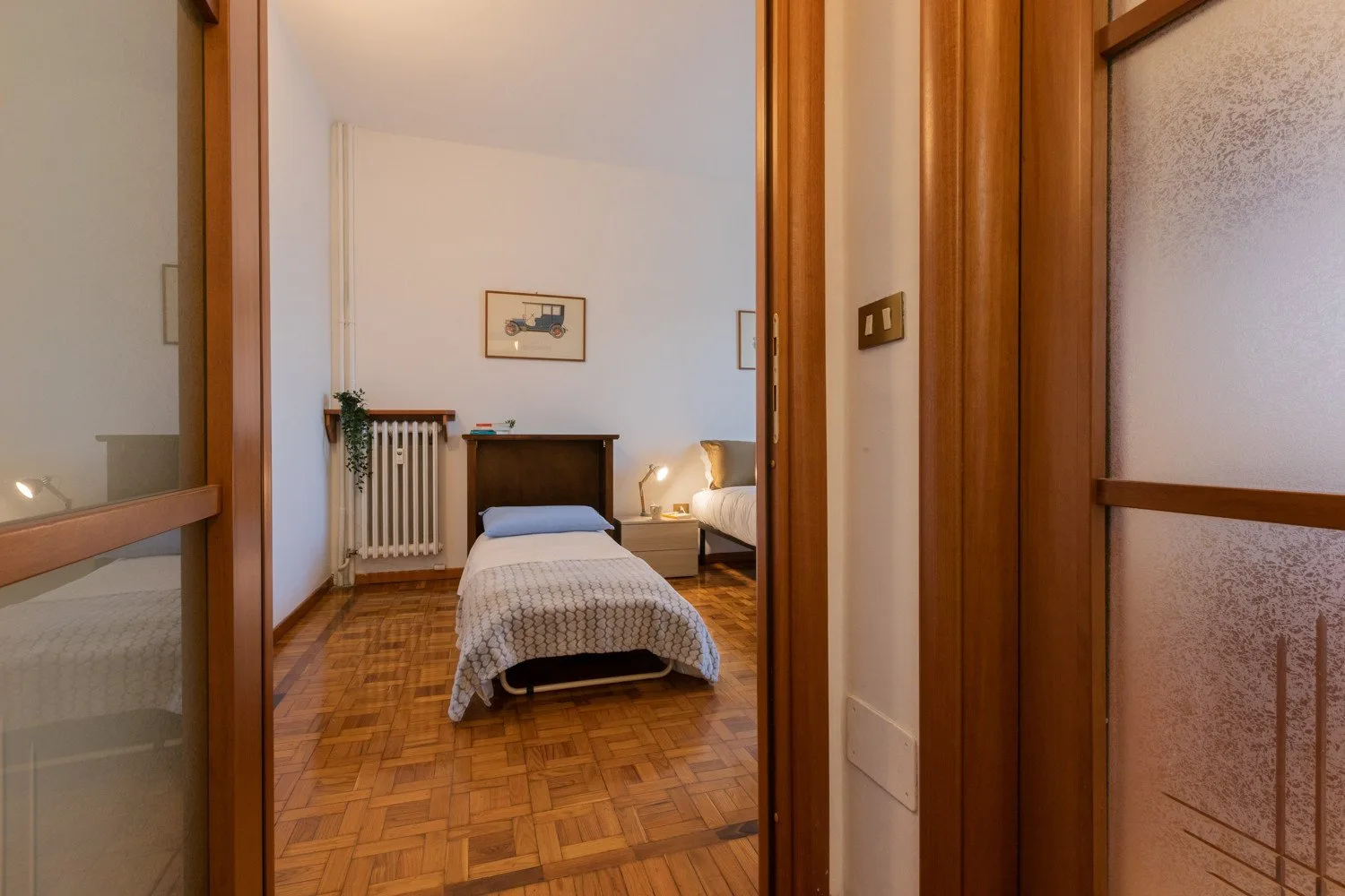 Un dormitorio con una cama individual, un radiador y suelo de parquet.