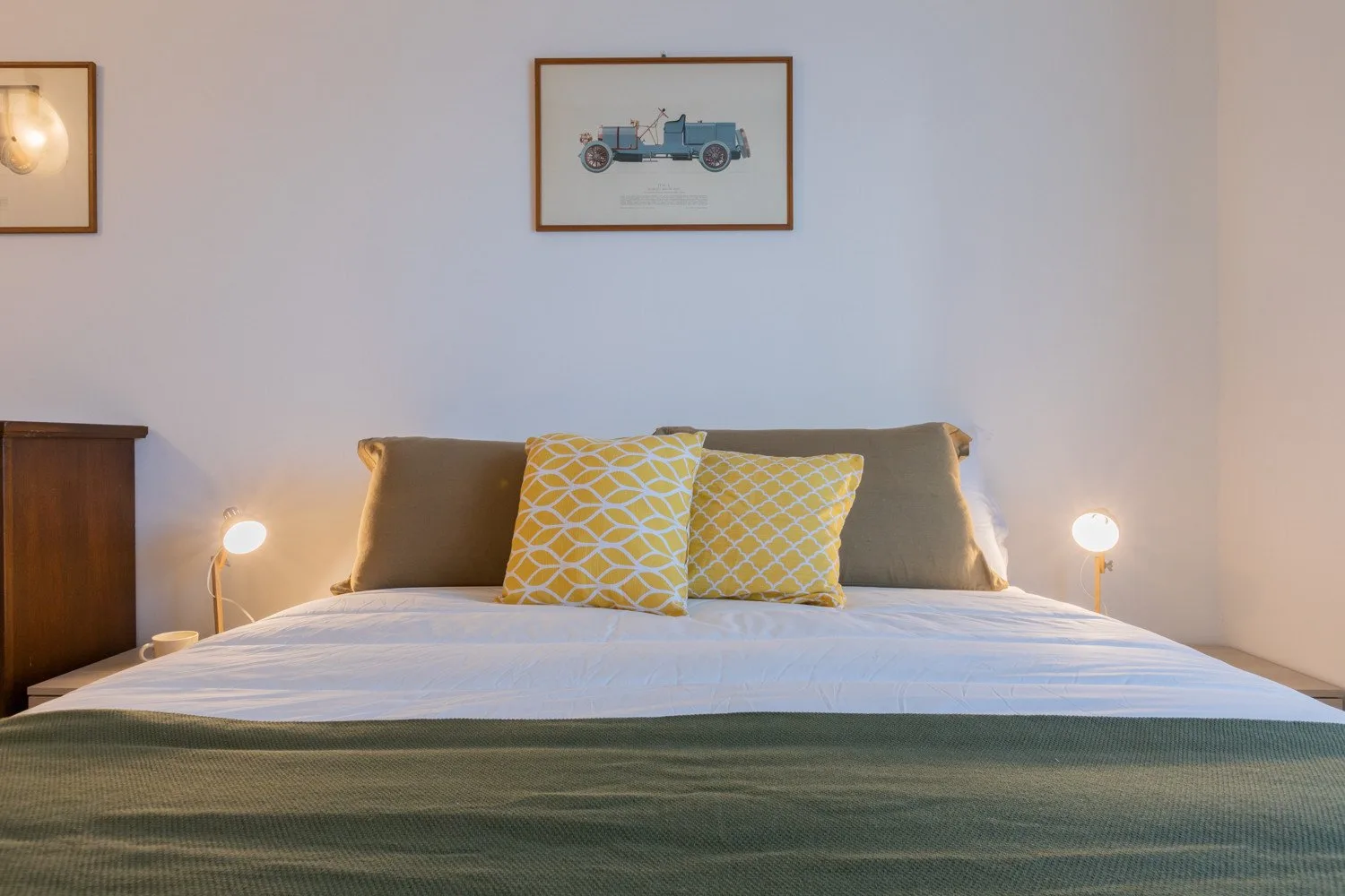 Una cama bien tendida con cojines estampados y lámparas de noche.