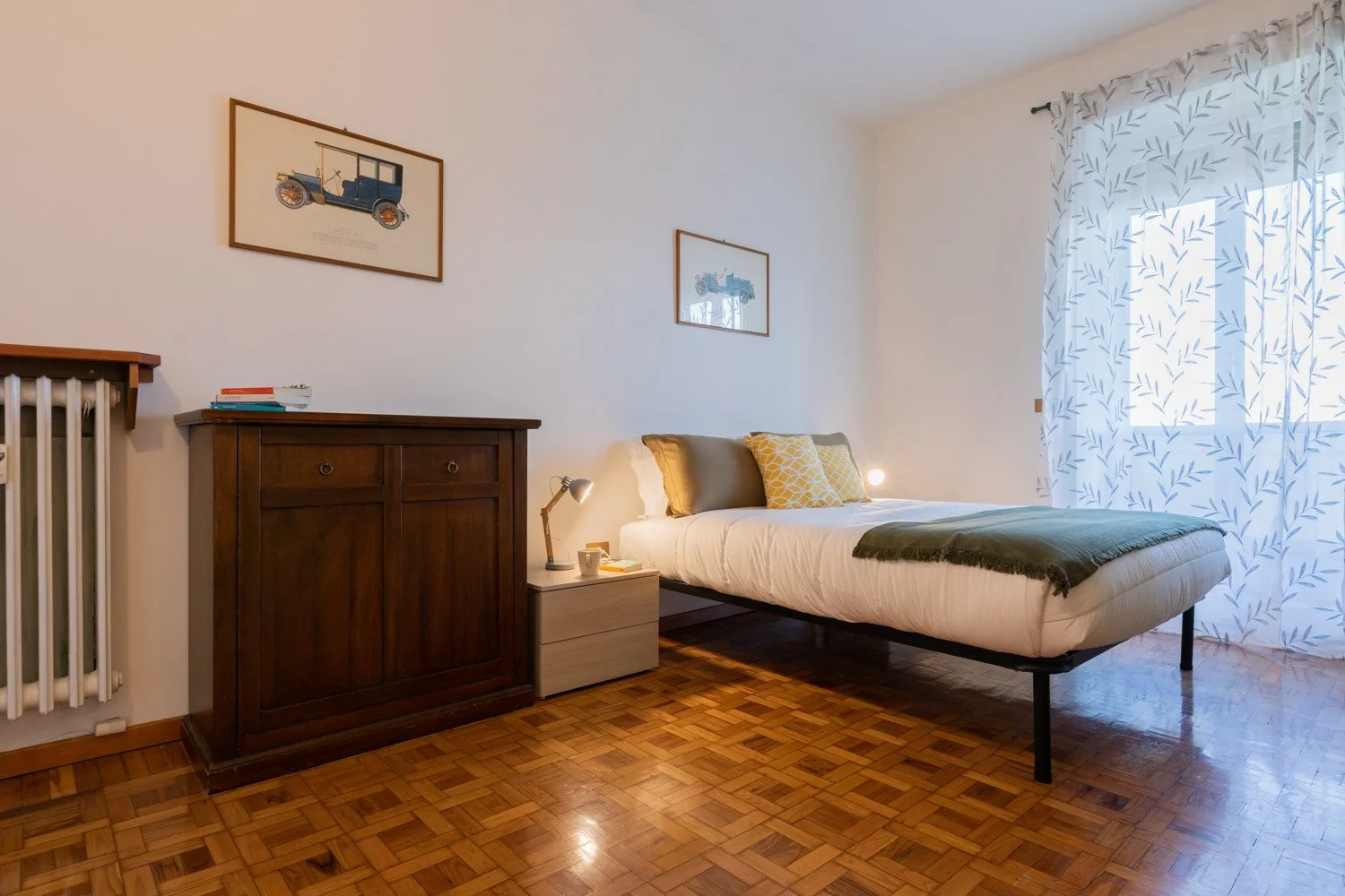 Un dormitorio con una cama, una cómoda de madera oscura y cortinas estampadas.