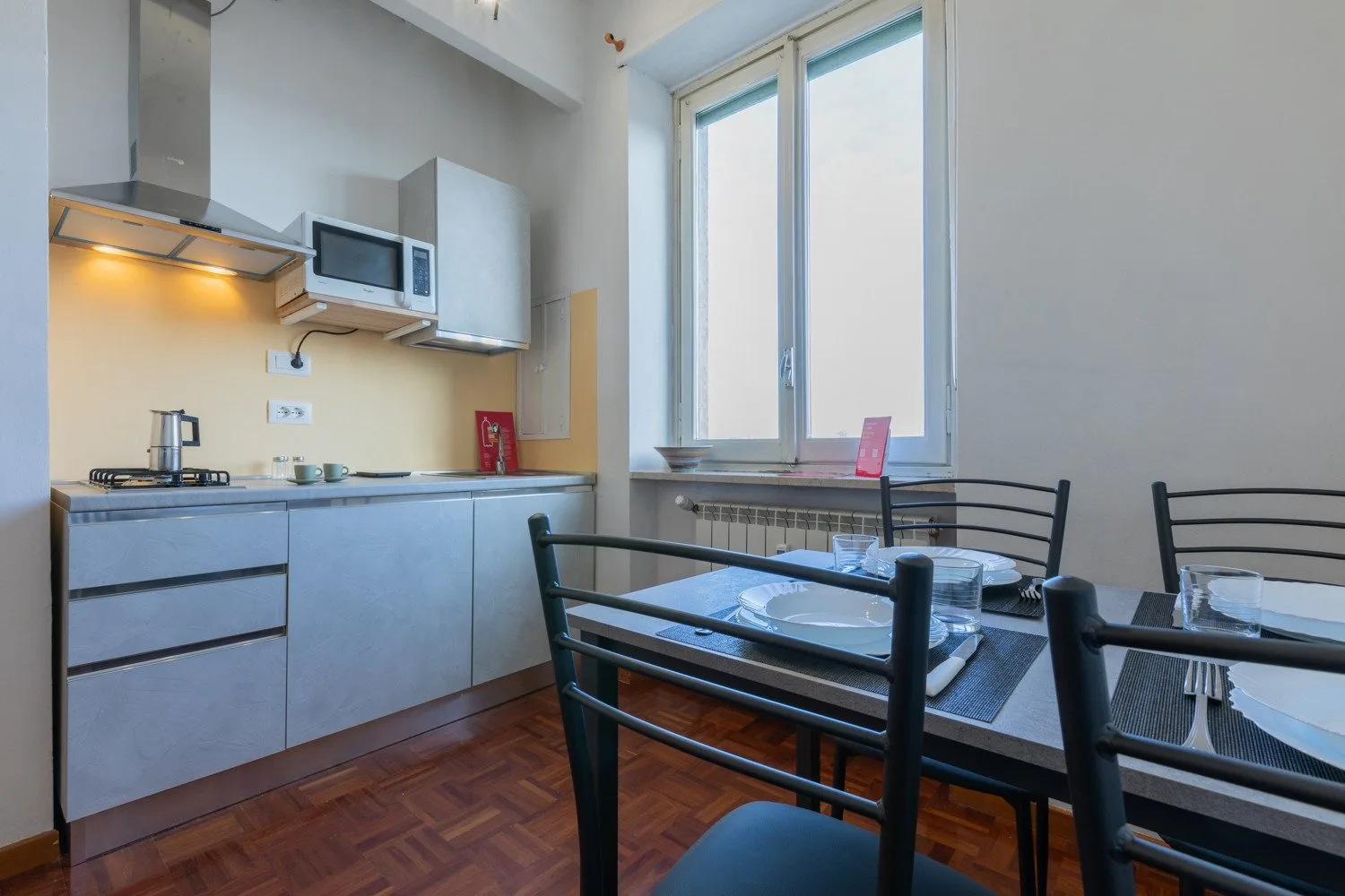 Una cocina y comedor con una mesa junto a una ventana grande.