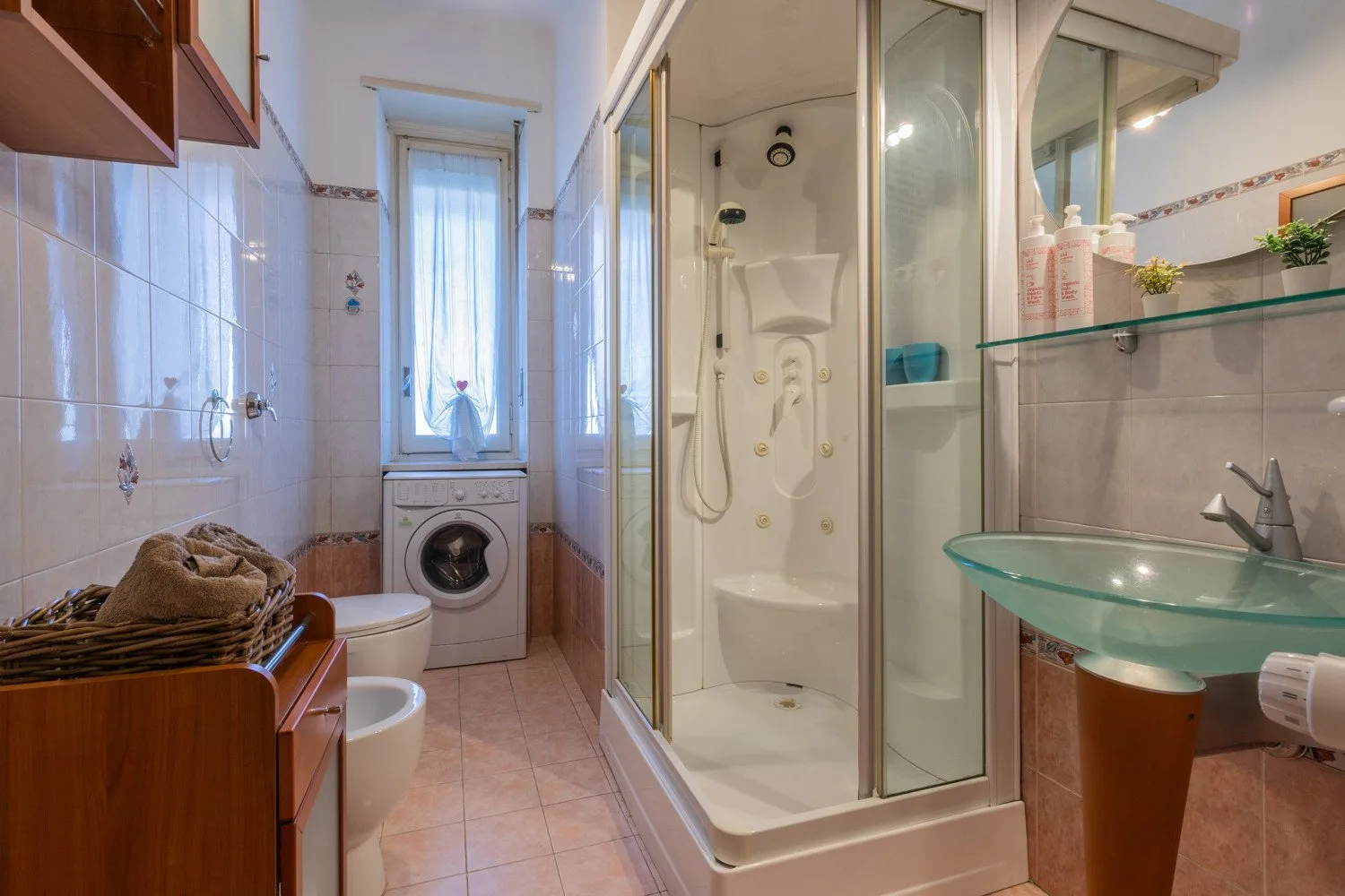 Un baño con ducha de vidrio, lavabo y lavadora.