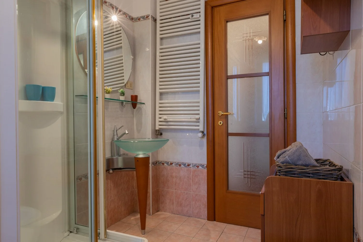 Un baño con ducha de vidrio, lavabo y puerta de madera.