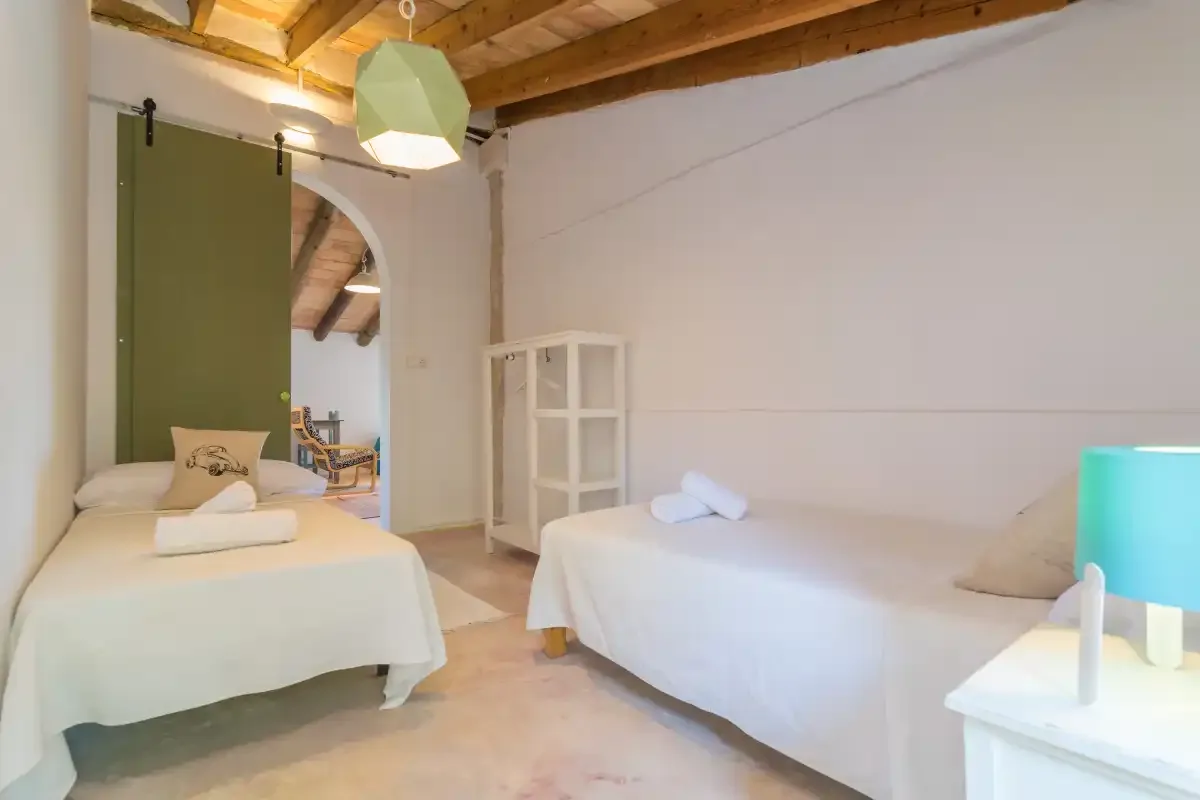 A bedroom with two beds, a wooden ceiling, and a white cabinet.