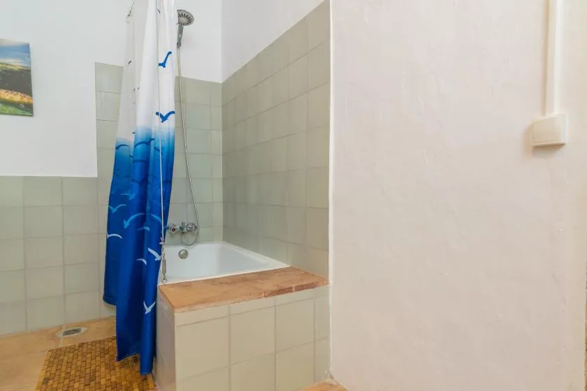 A tiled bathroom with a bathtub and blue shower curtain.